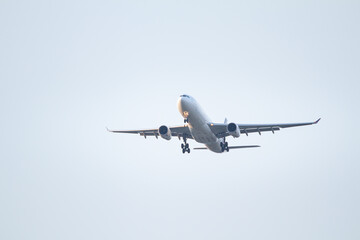 Fototapeta premium Large twin engine passenger jet viewed from below during final landing approach with extended gear and spacious sky background.