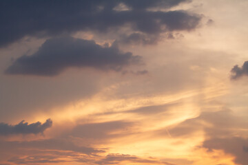 Obraz premium Warm sunset colors blend with layered clouds and fading daylight, creating a peaceful atmospheric sky scene with dramatic natural textures and glowing tones.