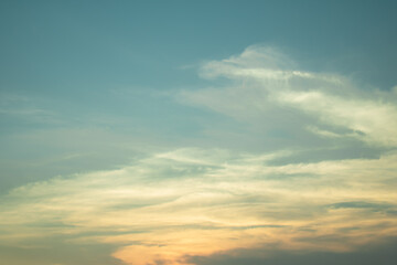 Obraz premium Delicate pastel clouds floating across a serene blue sky with warm evening tones, creating a peaceful atmospheric background for nature and design projects.
