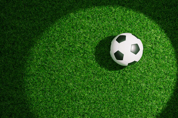Obraz premium classic black and white soccer ball resting on a lush green grass field, illuminated by a dramatic spotlight effect creating a circular glow and soft shadows on the turf. Football wallpaper. Soccer