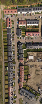 Aerial view of modern residential housing development with rows of houses featuring solar panels and green gardens.