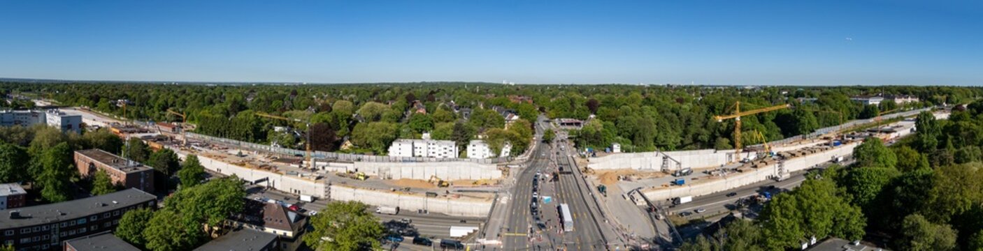 Aerial view of the large-scale highway construction site in Bahrenfeld featuring yellow cranes and concrete walls surrounded by green trees in Hamburg, Hamburg, Germany.