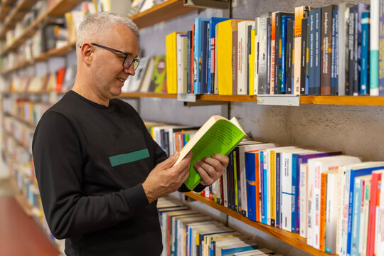 Mature man reading book discovering knowledge in library