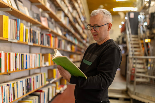 Man in glasses enjoying reading book in bookstore