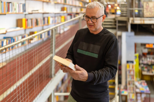 Mature man reading book in a multilevel bookstore