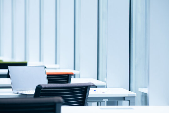 Empty shared workspace. Open laptop on the desk in the classroom. Modern design and architecture. Text-space. Indoor shot