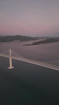 High-angle perspective of Peljesac Bridge over the Adriatic Sea during twilight. Professional drone photography of Croatia's landmark infrastructure at golden hour.