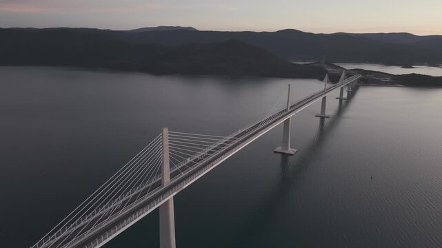 High-angle perspective of Peljesac Bridge over the Adriatic Sea during twilight. Professional drone photography of Croatia's landmark infrastructure at golden hour.