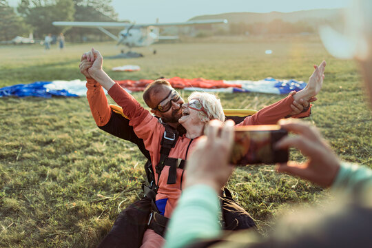 Senior woman celebrates tandem skydive landing at airfield