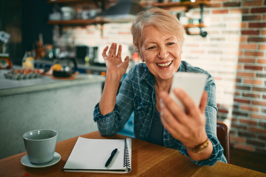Smiling senior woman video calling in home kitchen