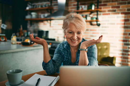 Smiling senior woman on video call in home kitchen