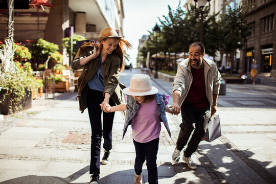 Parents and daughter running and shopping on city street