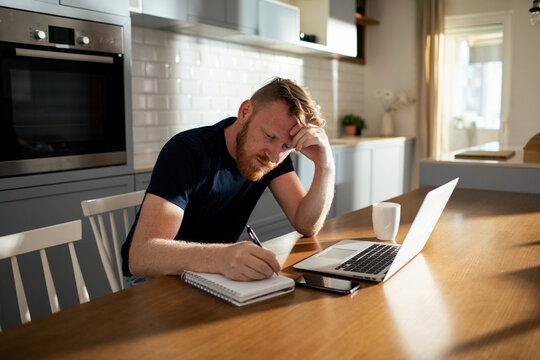 Stressed man working from home at kitchen table