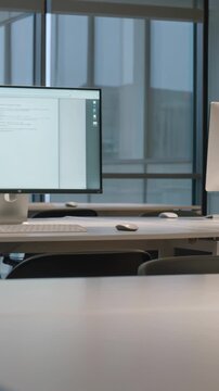 Empty office workspace with multiple monitors, slow pan shot, modern corporate interior with large windows daylight 4K
