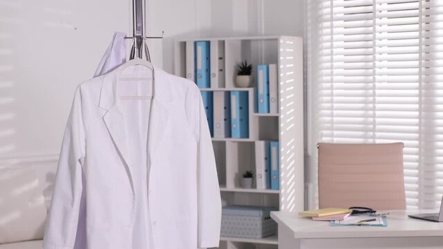 Woman hanging medical worker uniform on rack indoors, closeup