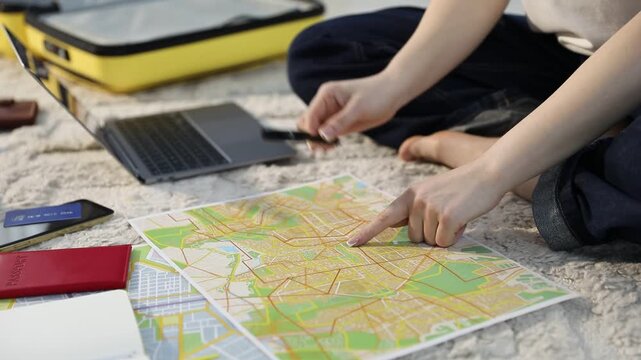 Planning trip. Woman looking at map on floor indoors, closeup