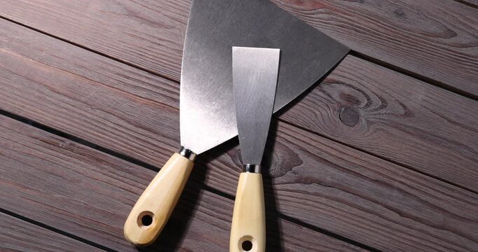 Putty knives on wooden table, spinning. Top view