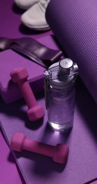 Woman putting sports equipment on purple background, closeup