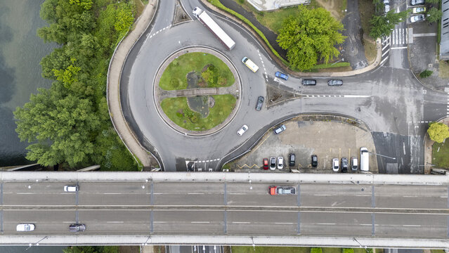 Aerial view of Ponte do Ribeirino bridge and a busy roundabout with vehicles and lush green trees in Ourense, Ourense, Spain.