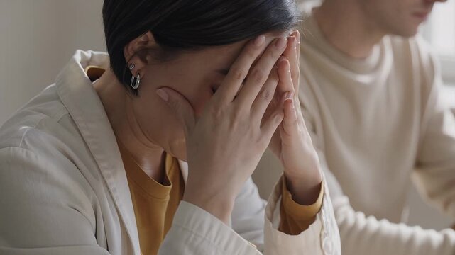 Stressed business woman covering face in hands during difficult meeting