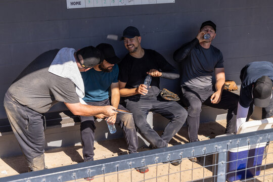 Baseball team sitting bench pointing at score, causing overlay stats over glove while planning