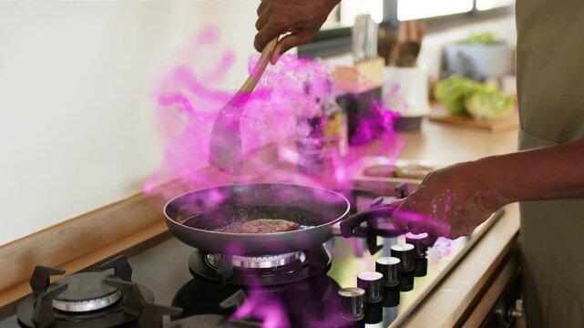 Cook placing patty on lit burner, pressing with spatula to sear while magenta vapor wrapping hand
