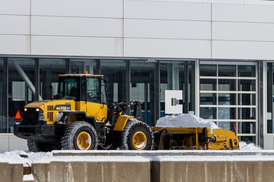 MONTREAL, CANADA, 24 December 2025 : Snowplow clearing snow outside commercial building winter maintenance equipment