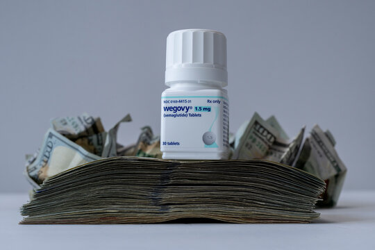 A new bottle of Wegovy pills on a pile of cash.