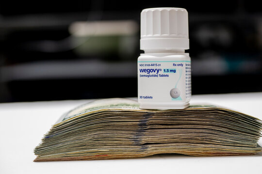 A new bottle of Wegovy pills on a pile of cash.