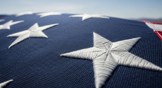 Close-up view of the embroidered white stars on the blue field of an American flag, symbolizing patriotism and national pride.