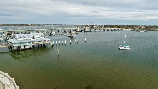 Aerial view of the Bridge of Lions and a marina with sailboats and a waterfront building on stilts in St. Augustine, Florida, United States.