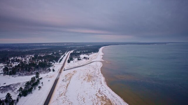 Drone shot of snow covered landscape in Northern Michigan with US highway 2 and lake superior in frame
