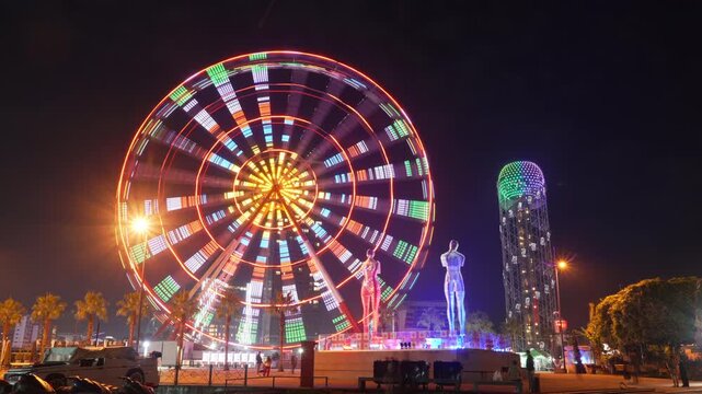 Timelapse of a spinning illuminated Ferris wheel in Batumi evening, Alphabet Tower illumination, Ali and Nino statue moving, sightseeing in Georgia, Adjara