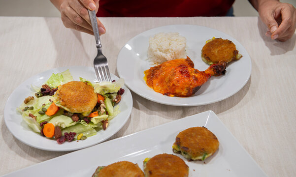Mano femenina de mujer con tenedor comiendo alimentos, con ensalada y pollo en salsa con arroz al vapor, estilo de vida y concepto de comida familiar saludable.