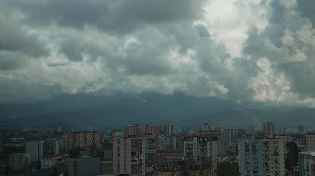 Storm clouds are scudding over a city at the foot of the Caucasus Mountains timelapse. Storm warning, climate change, environmental protection. Problem of urban air pollution