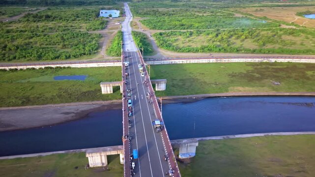 Aerial View of Red Arched Bridge Over Water with Coastal City Skyline