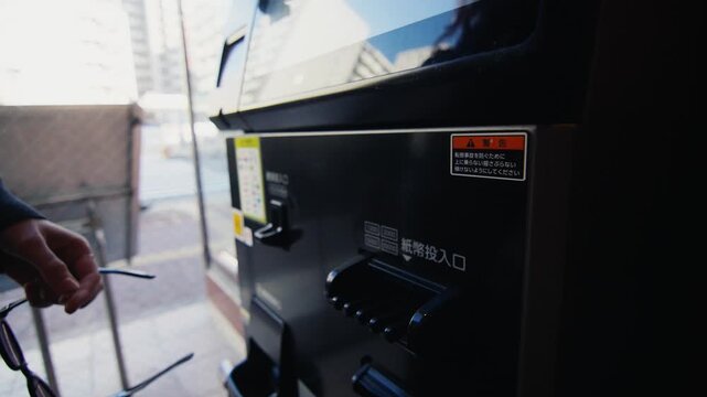 Woman inserting japanese yen into vending machine