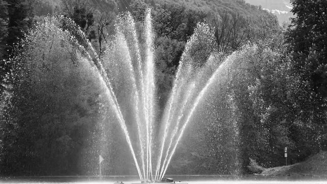 Close-up perspective of a multi-jet fountain on Walensee, water streams fanning outward with fine mist and textured droplets.