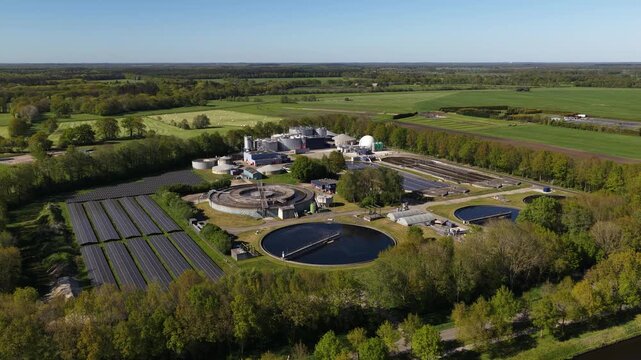 High angle perspective showing a modern sewage and water purification facility with clarifiers and solar panels, essential for environmental protection and recycling in a green rural area