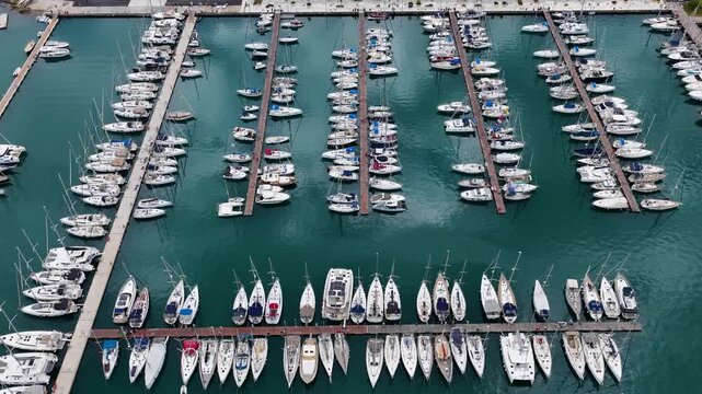 Overhead aerial drone shot of Gouvia Marina docks with luxury yachts and sailboats, Corfu, Greece. Nautical pattern of moored boats in a Mediterranean port.