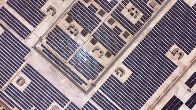 Top-down view of a large commercial rooftop covered with rows of solar panels and HVAC units, showcasing urban renewable energy infrastructure at scale