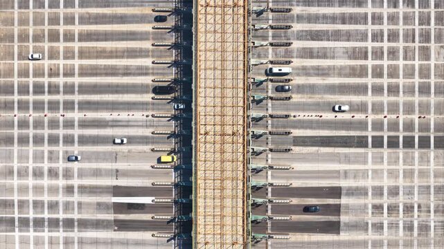 Drone view showing vehicles driving through an extensive toll booth plaza on a multi-lane highway, highlighting modern transportation infrastructure and the payment collection system