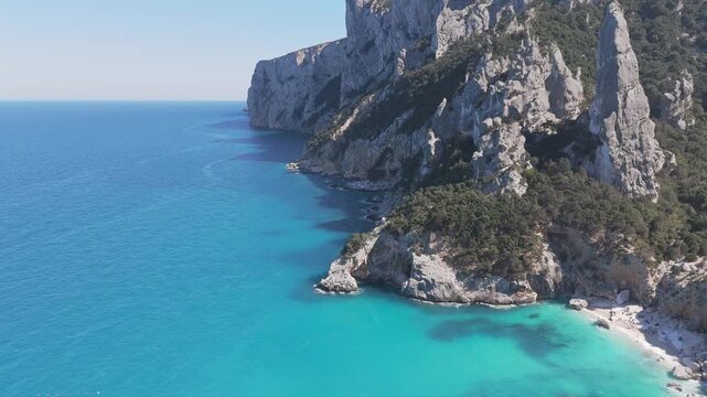 Steep coastal cliffs descending into turquoise sea at Cala Goloritze Baunei Sardinia, drone