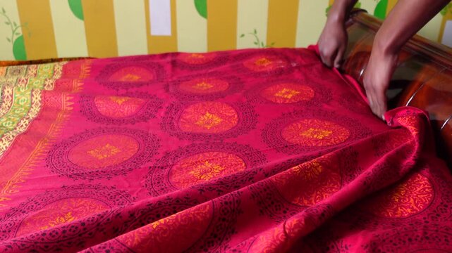 Hands Arranging Red Patterned Bedsheet on Bed
