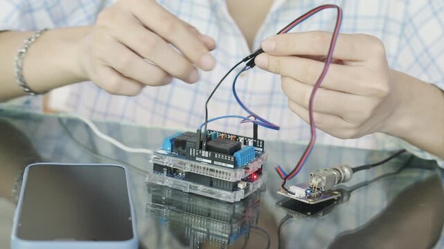 Close-up Hand of woman is connecting the oxygen meter connector to the microcontroller and displaying the results on smartphone screen.