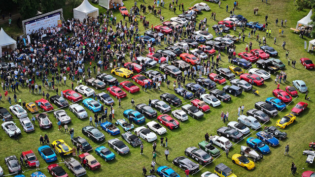 La Chapelle-de-Guinchay, France - 01 June 2024: Aerial view of a large gathering of classic and modern sports cars parked in rows on a green field during an outdoor automotive event.