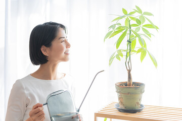 観葉植物にジョウロで水やりする女性 © polkadot