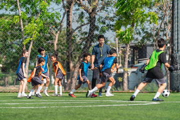 Fototapeta premium World cup concept with soccer ball or football player, youth soccer practice on outdoor field with coach and children training together