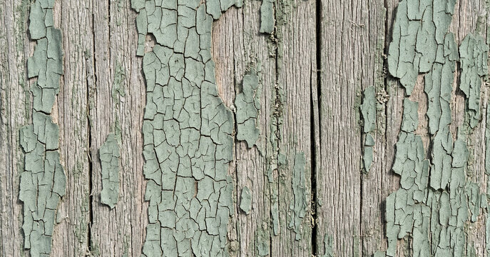 Close-up of old, weathered wood with peeling turquoise paint, showcasing the rough texture and aged appearance of the surface.