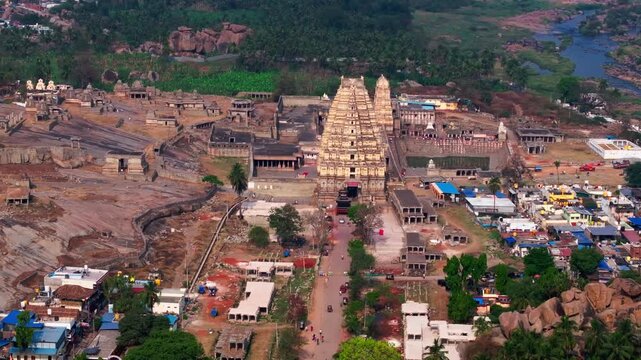 Virupaksha Temple raja gopuram with Manmatha Tank, temples ruins, farming land and Tungabhadra river at hampi, karnataka, india. day time, semi orbit shot, drone shot, 4k.